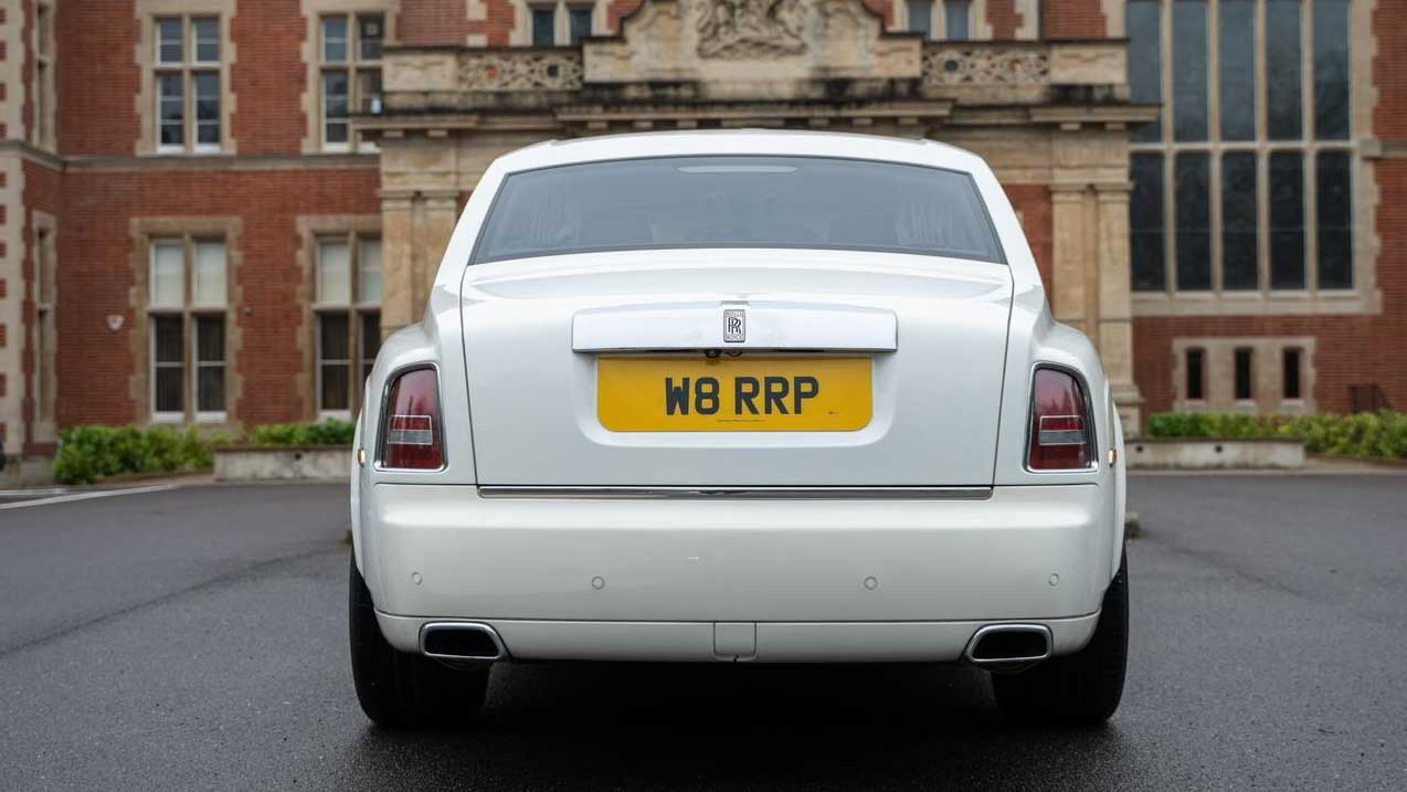 Rear view of white Rolls-Royce Phantom Series II EWB parked outside luxury venue.