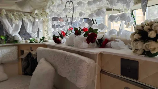 Wedding decorated interior of classic Volkswagen campervan with flowers, ribbons and cream seating.
