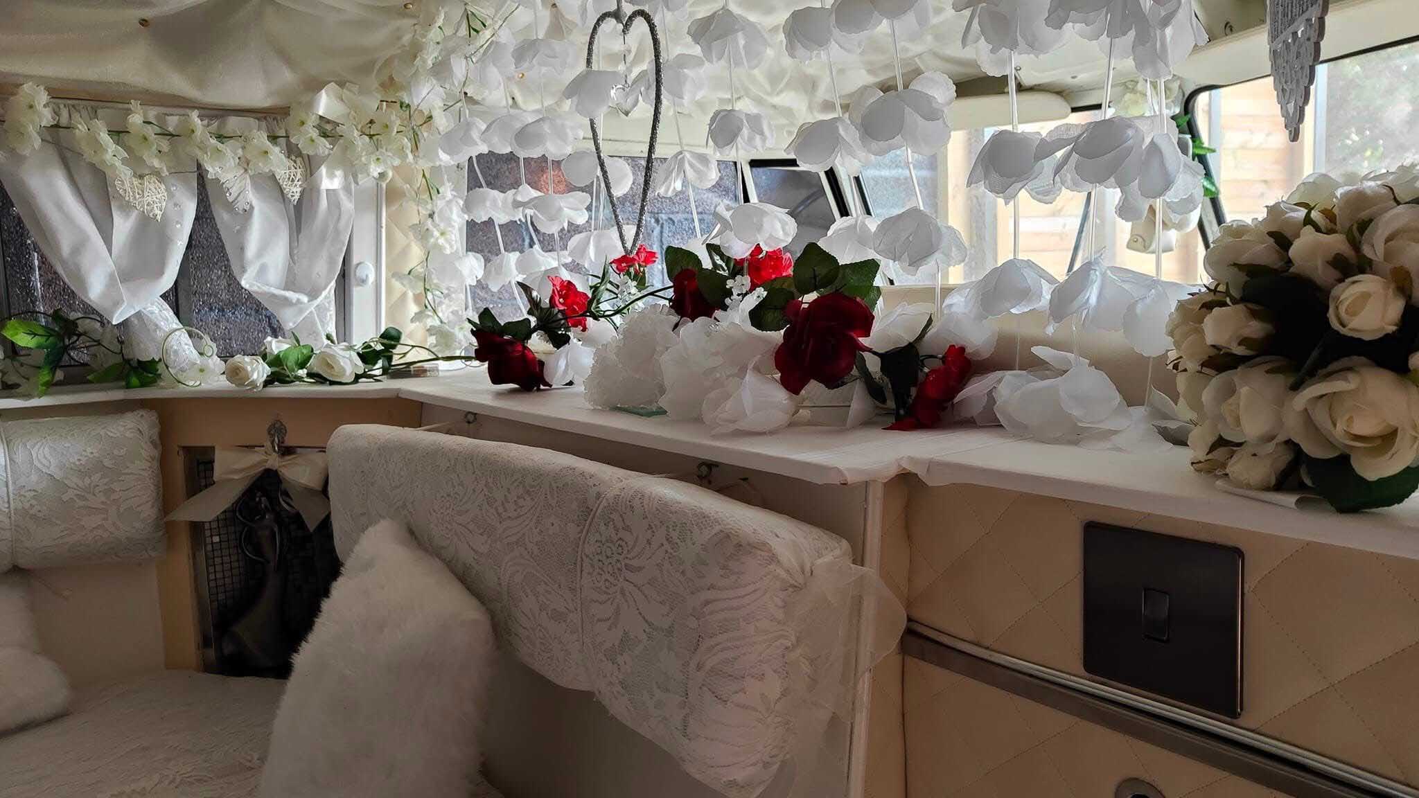 Wedding decorated interior of classic Volkswagen campervan with flowers, ribbons and cream seating.