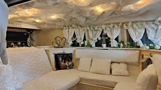 Spacious rear passenger area inside classic Volkswagen campervan with cream upholstery and wedding decorations.