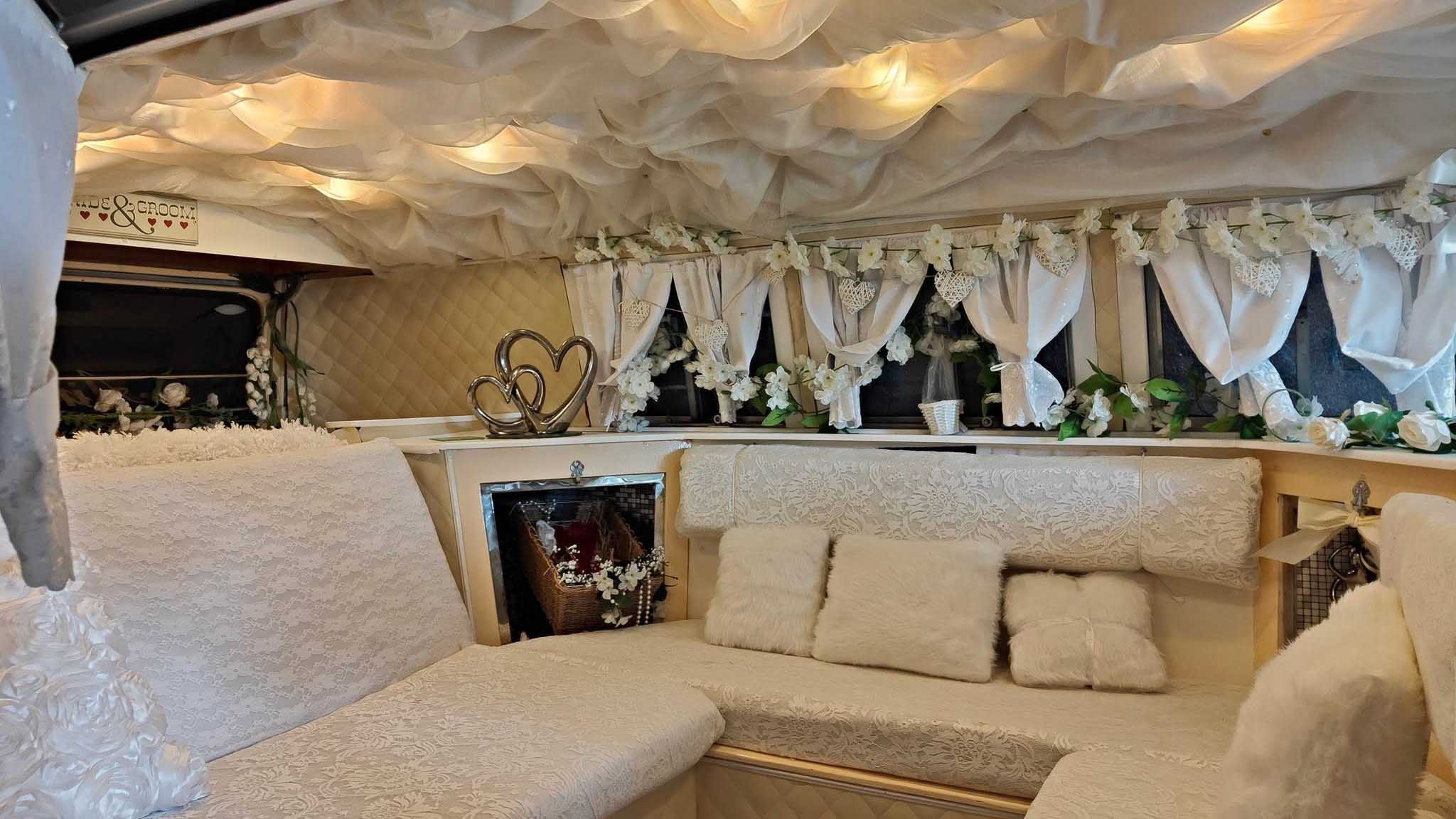 Spacious rear passenger area inside classic Volkswagen campervan with cream upholstery and wedding decorations.