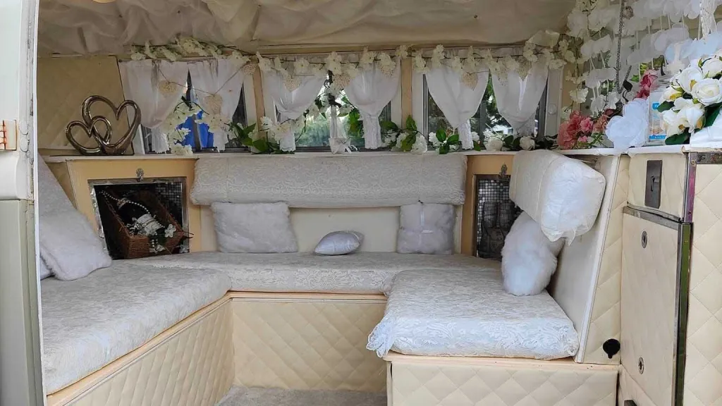 Cream upholstered rear seating inside Volkswagen Split Screen campervan arranged for wedding transport.