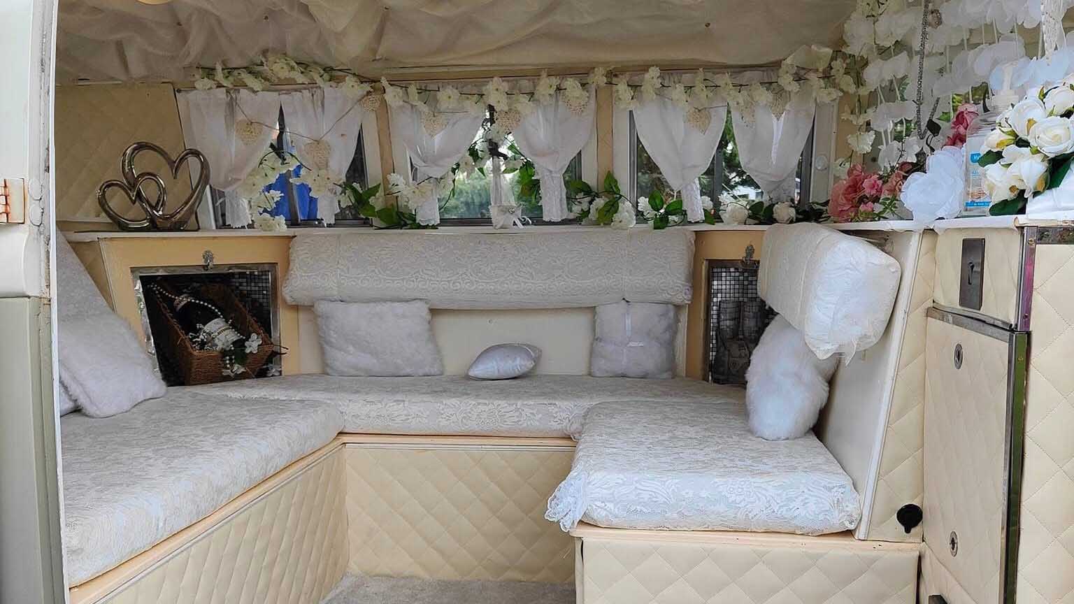 Cream upholstered rear seating inside Volkswagen Split Screen campervan arranged for wedding transport.