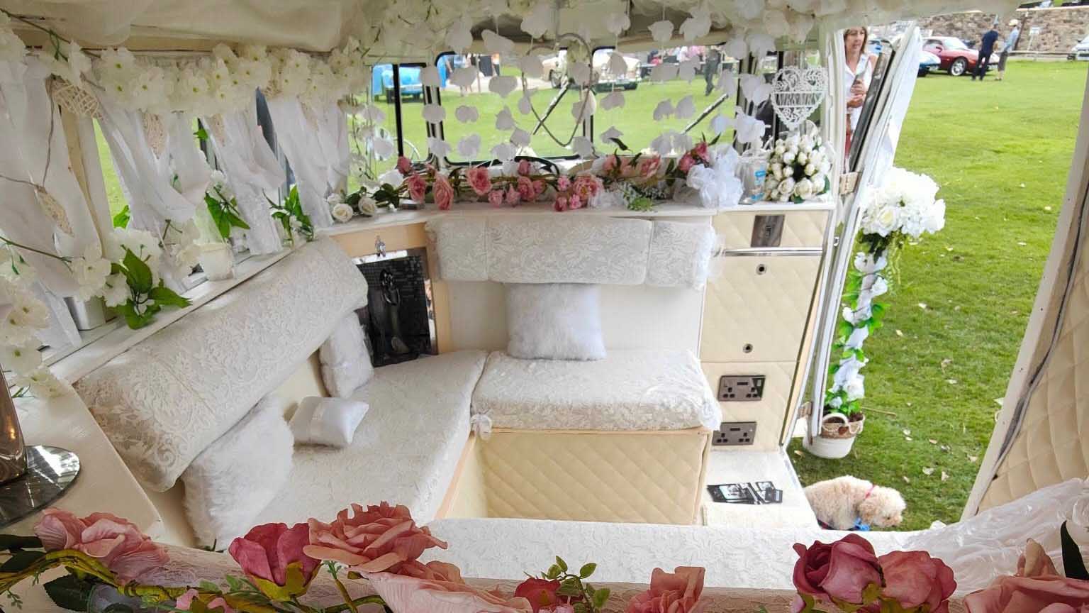 Beautifully decorated wedding interior inside classic Volkswagen Split Screen campervan with floral displays.