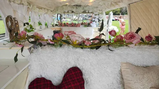 Floral wedding decorations and soft furnishings inside ivory and sage green Volkswagen campervan.