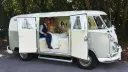 Wedding couple seated inside ivory and sage green Volkswagen Split Screen campervan in Devon.
