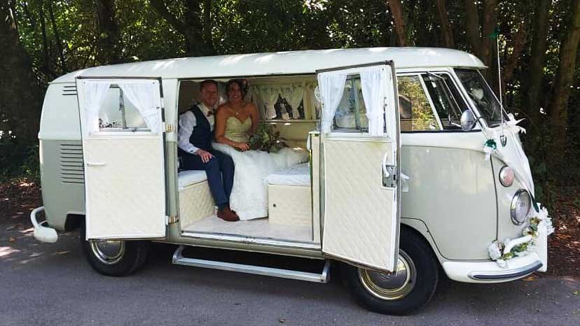Wedding couple seated inside ivory and sage green Volkswagen Split Screen campervan in Devon.