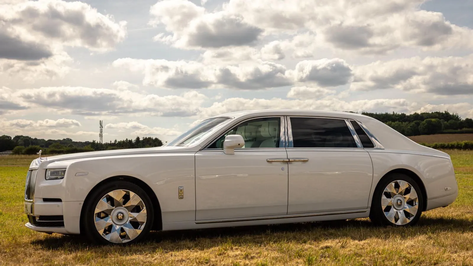 Left side view of White Rolls-Royce Phantom 8 with chrome wheels