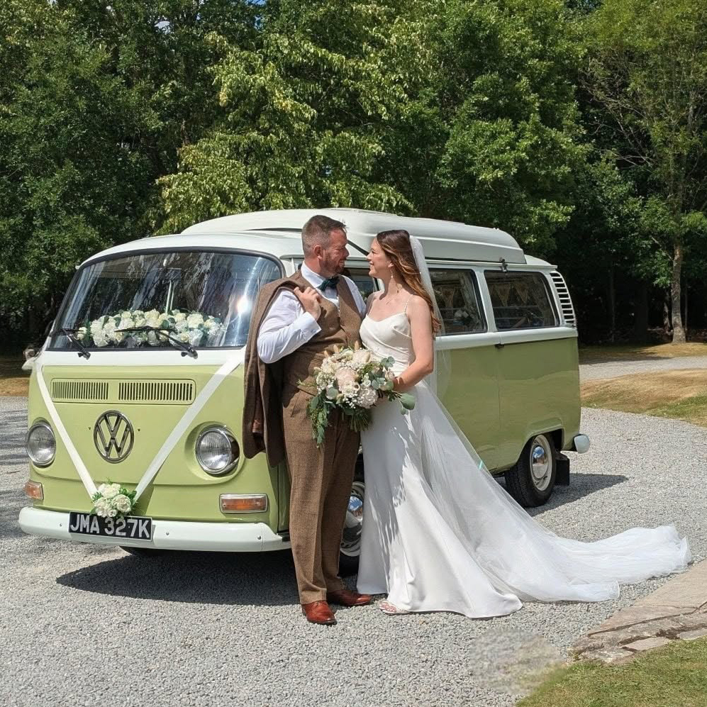 Bride and groom standing beside a green and cream VW campervan wedding car at Belfry Hotel in Sutton Coldfield.