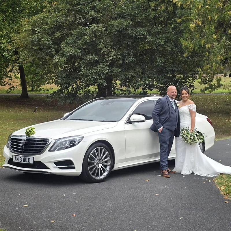 Bride and groom with a white Mercedes wedding car outside Dudley Registry Office in the West Midlands.