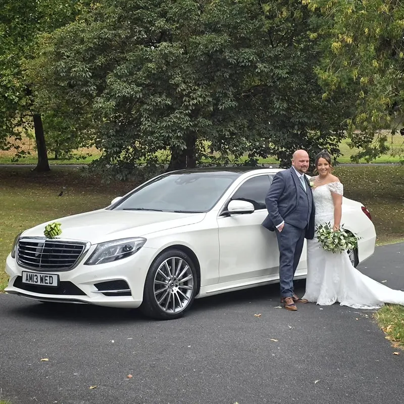 Bride and groom with a white Mercedes wedding car outside Dudley Registry Office in the West Midlands.