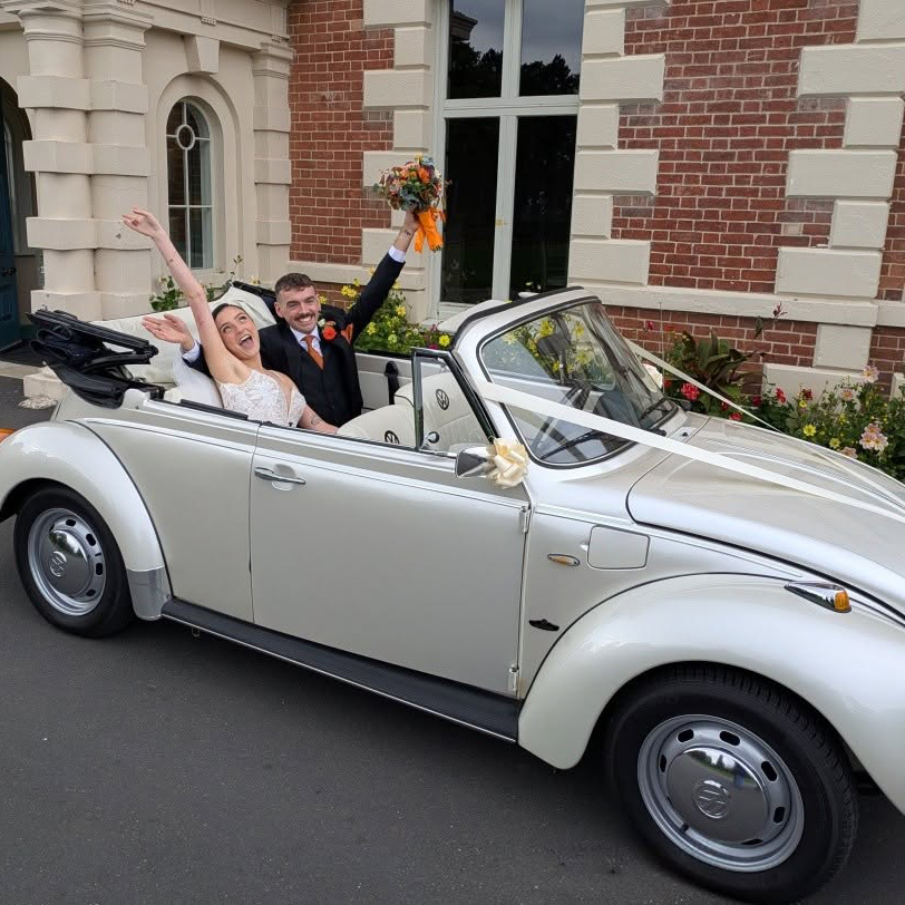 Bride and groom celebrating in a white VW Beetle convertible wedding car at Lightwoods Park in Bearwood.