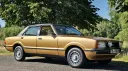 Front side view of gold 1977 Ford Cortina Mk4 Ghia with chrome trim and alloy wheels.