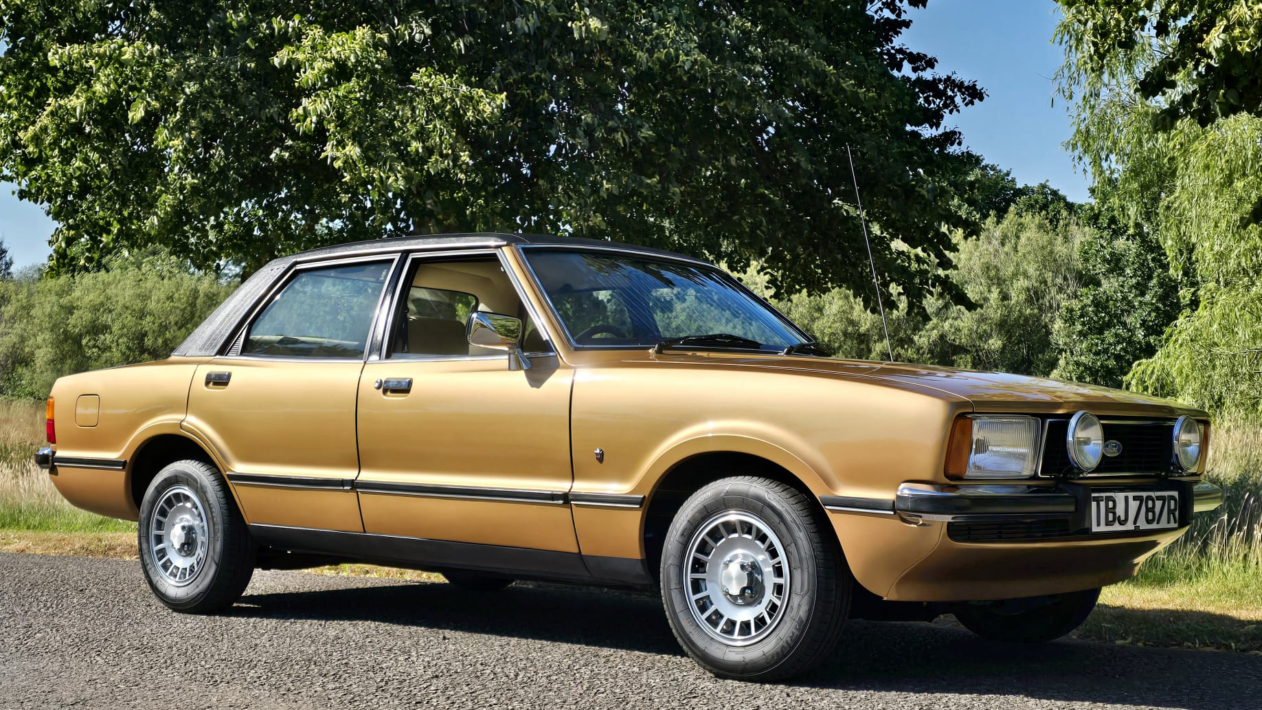 Front side view of gold 1977 Ford Cortina Mk4 Ghia with chrome trim and alloy wheels.