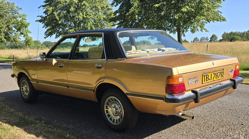 Rear left side view of gold Ford Cortina Mk4 Ghia showing classic saloon styling.