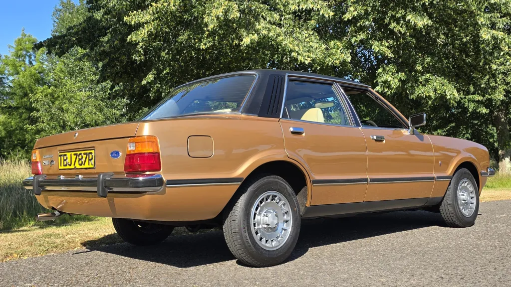 Rear right side view of 1977 Ford Cortina Mk4 Ghia in metallic gold with chrome bumpers.
