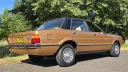 Rear right side view of 1977 Ford Cortina Mk4 Ghia in metallic gold with chrome bumpers.