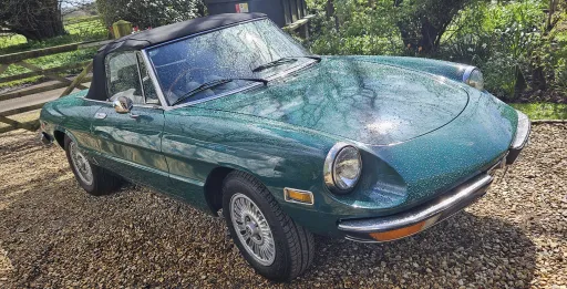 Front three quarter view of green Alfa Romeo Spider Veloce 2000 convertible parked on gravel driveway.