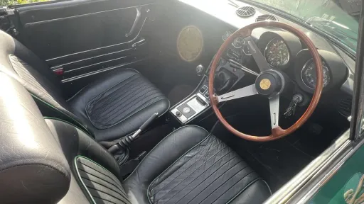 Black leather interior and wooden steering wheel inside classic Alfa Romeo Spider Veloce 2000.