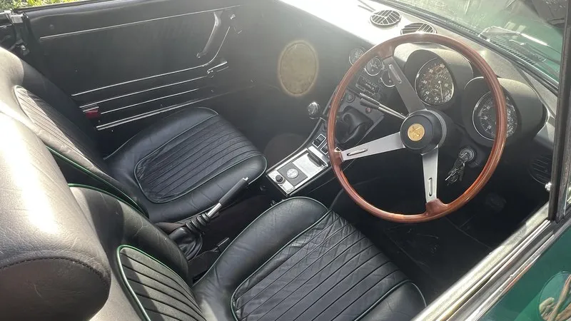 Black leather interior and wooden steering wheel inside classic Alfa Romeo Spider Veloce 2000.
