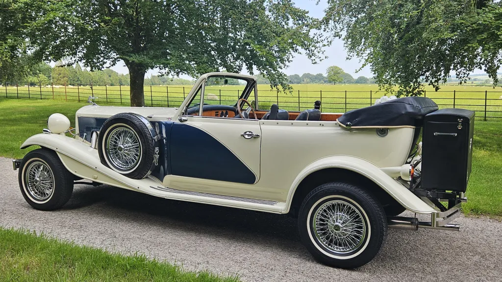 Rear side view of blue and ivory Beauford convertible with the roof folded down.