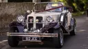 Front view of burgundy and cream Beauford convertible with chrome grille, spotlights and wedding ribbons in Salisbury.
