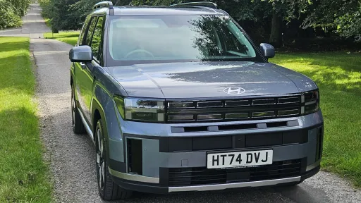 Front view of blue Hyundai Santa Fe Ultimate HEV parked on tree lined driveway in Wiltshire.