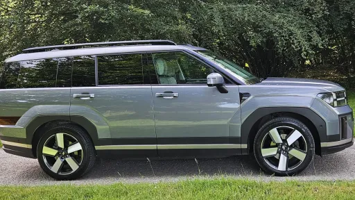 Full right side profile of blue Hyundai Santa Fe Ultimate HEV seven seater SUV parked outdoors.