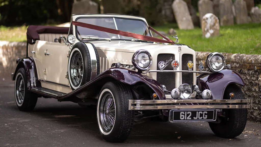 Front view of burgundy and cream Beauford convertible with chrome grille, spotlights and wedding ribbons in Salisbury.