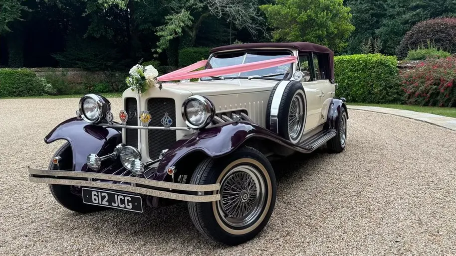 Front angled view of burgundy and cream Beauford convertible decorated with flowers and wedding ribbons in Salisbury.
