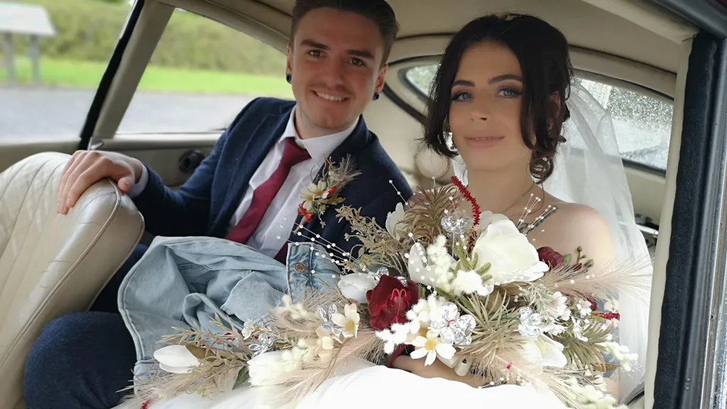 Bride and groom seated inside red 1969 Jaguar E Type with cream interior after their wedding ceremony.