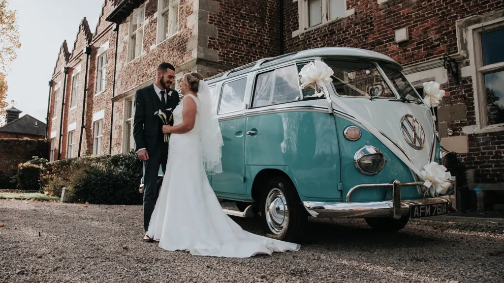 Blue and white 1964 Volkswagen Split Screen Samba campervan parked outside historic wedding venue in North Wales.