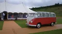 Red and white 1962 Volkswagen Split Screen 23 Window Microbus parked outside wedding marquee.
