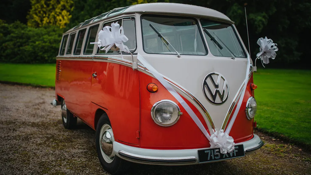 Front three quarter view of red and white 1962 Volkswagen Split Screen 23 Window Microbus decorated for a wedding.