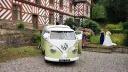 Cream and green Volkswagen Split Screen campervan parked outside traditional countryside wedding venue.