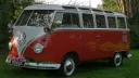 Left side view of red and white Volkswagen Split Screen 23 Window Microbus with chrome bumpers and safari roof windows.