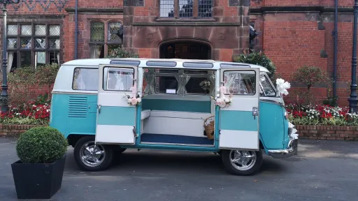 Right side view of turquoise and white Volkswagen Split Screen campervan with rear doors open showing the interior.