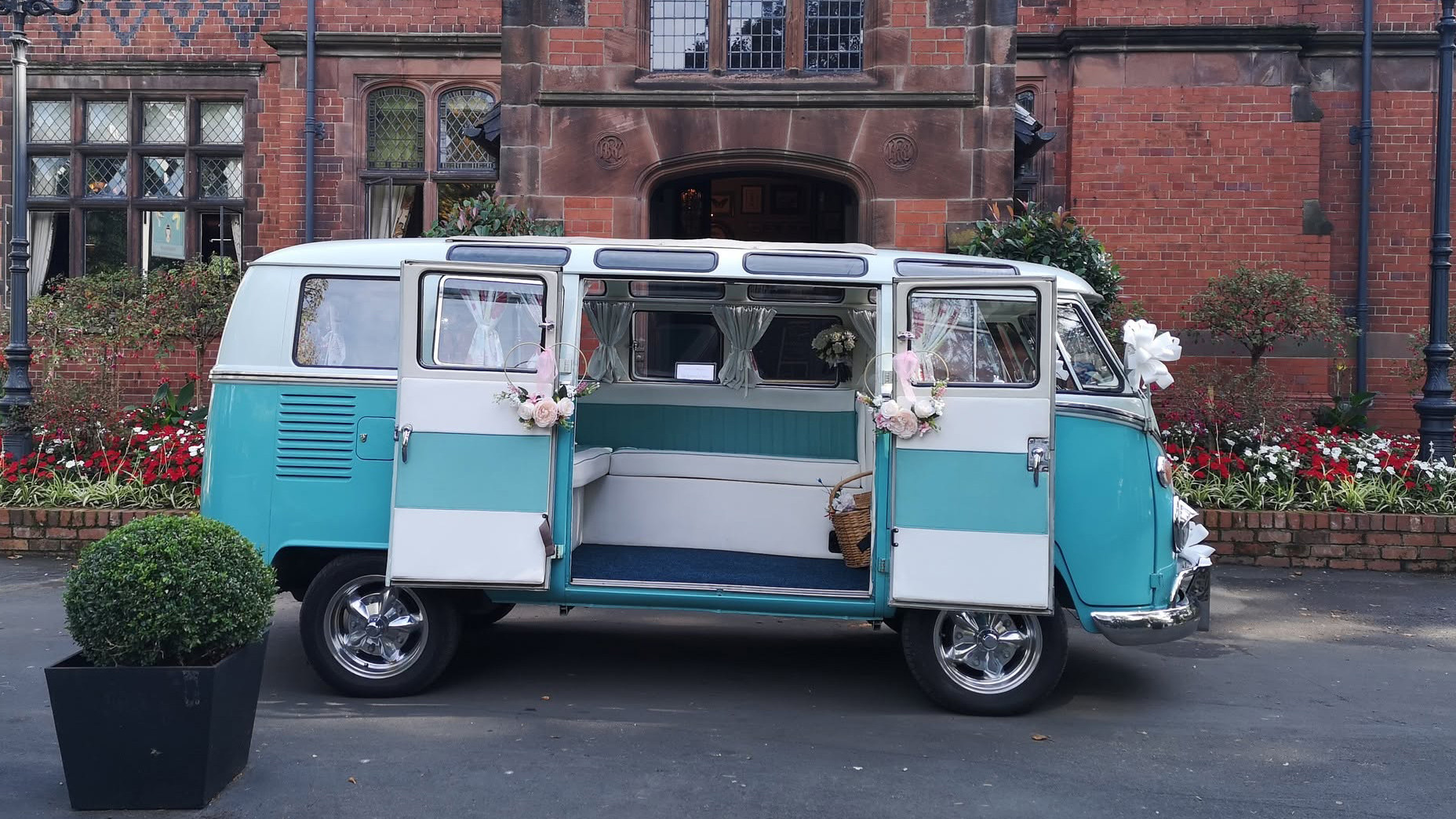 Right side view of turquoise and white Volkswagen Split Screen campervan with rear doors open showing the interior.