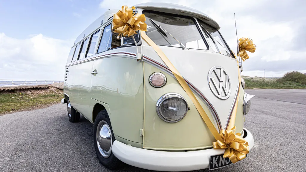 Front three quarter view of cream and green Volkswagen Split Screen campervan decorated with wedding ribbons in Wrexham.