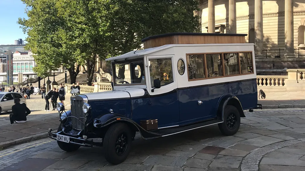 Navy blue and Old English White Asquith vintage wedding bus parked outside historic Liverpool buildings.