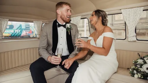 Bride and groom seated inside cream 1972 Volkswagen Split Screen campervan with cream interior.
