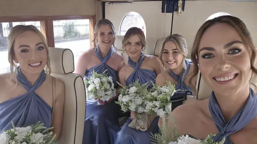 Smiling Bridesmaids seated inside navy blue Asquith vintage wedding bus with cream leather seating and spacious interior.