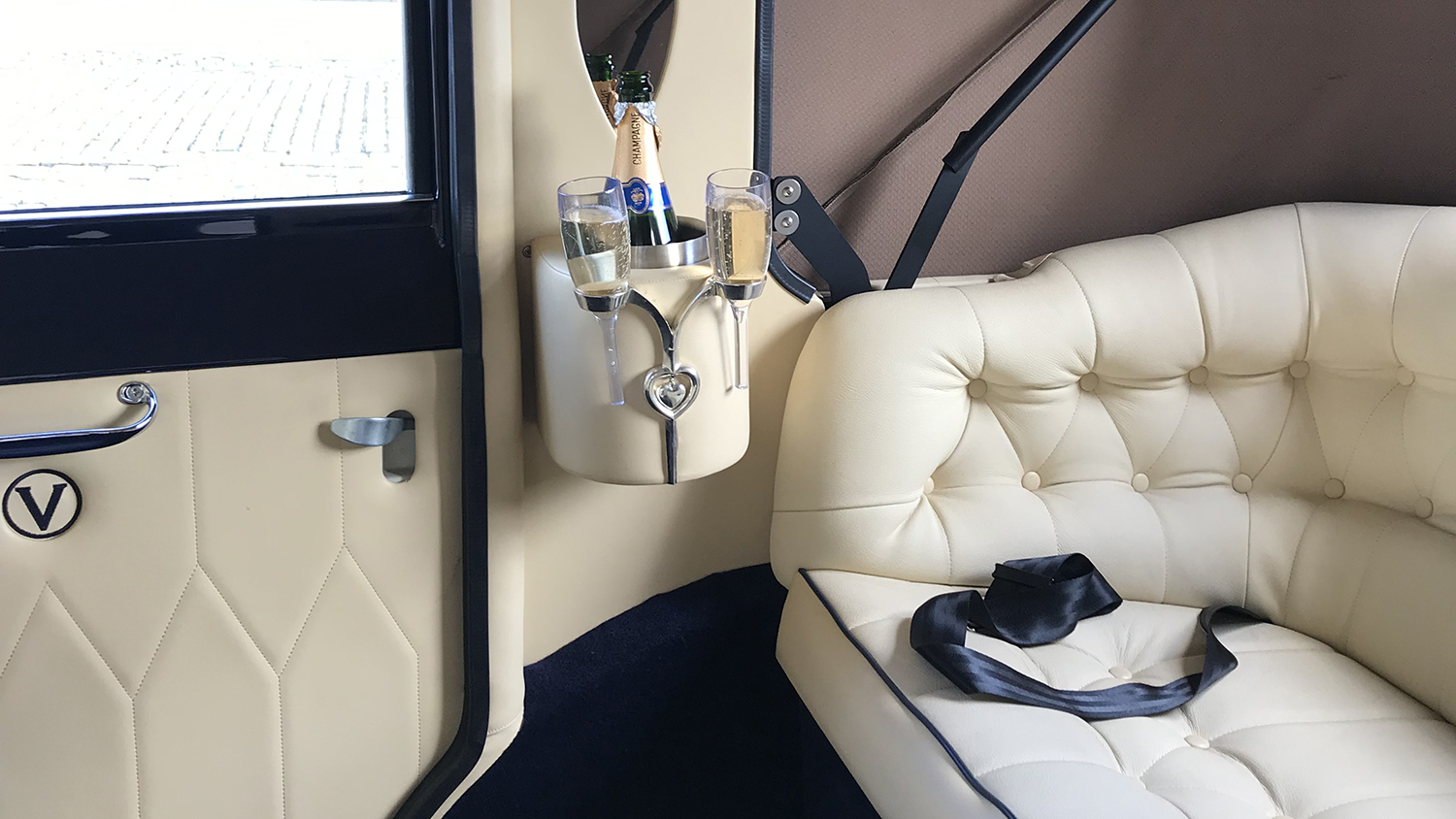 Champagne holder and cream leather interior inside ivory and navy blue Imperial Landaulette wedding car.