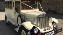 Front view of Old English White Asquith vintage wedding bus with chrome headlamps, classic radiator and side mounted spare wheel.