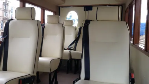 Cream leather passenger seats inside Asquith vintage wedding bus with polished mahogany window frames.