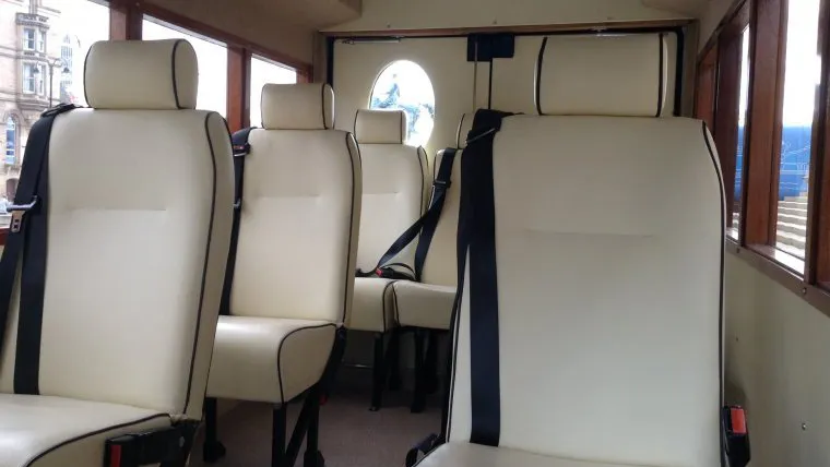 Cream leather passenger seats inside Asquith vintage wedding bus with polished mahogany window frames.