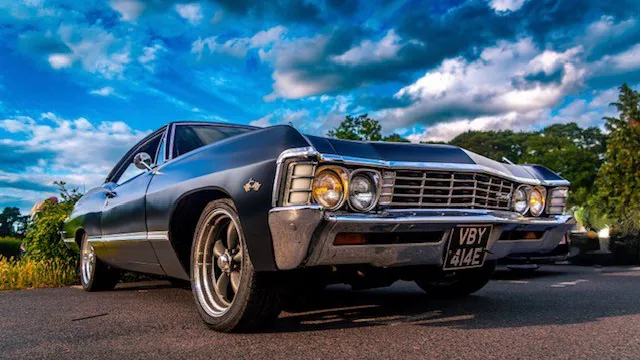 Front three quarter view of black 1967 Chevrolet Impala Fastback with chrome grille and period styling.