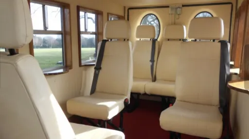 Cream leather passenger seats inside Old English White Asquith vintage wedding bus with deep red carpet