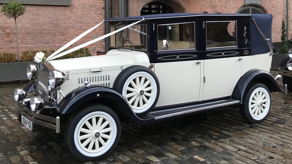 Ivory and navy blue Imperial Landaulette decorated with white wedding ribbons and chrome detailing.