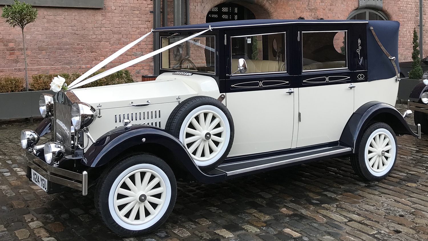 Ivory and navy blue Imperial Landaulette decorated with white wedding ribbons and chrome detailing.